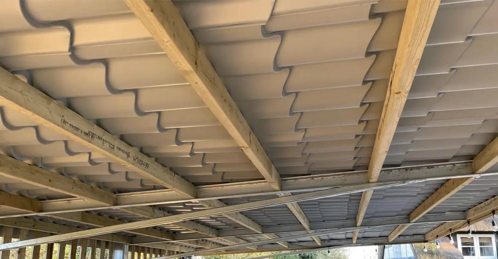 The underside of a single sided pitched roof with timber purlins and steel ceiling joists