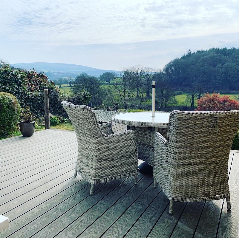 Composite decking terrace with rattan garden furniture overlooking rolling countryside hills
