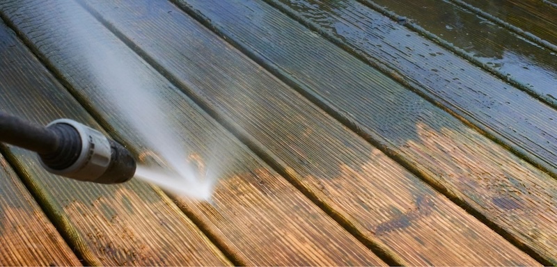 Power washing wooden decking to remove dirt and algae buildup