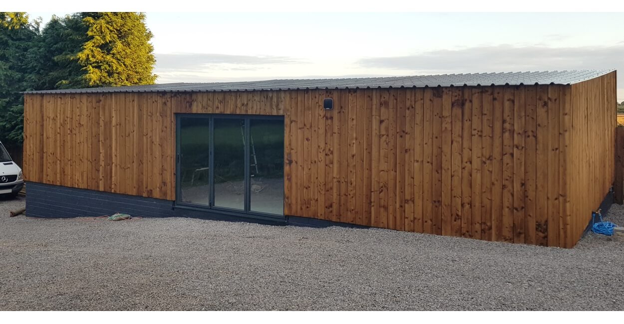 32/1000 Box Profile Roofing Sheets in Black contrast this timber-clad building