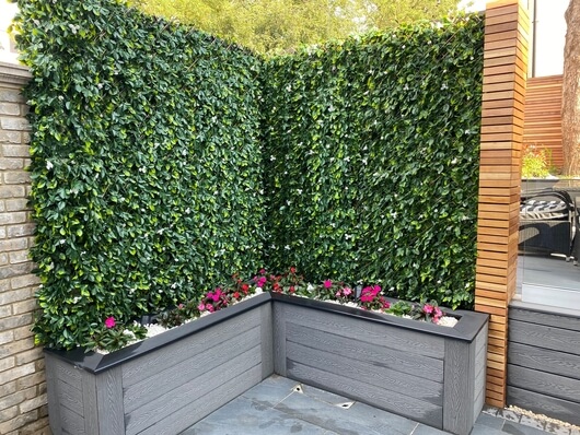 Raised flower beds constructed using Cladco Stone Grey composite decking boards, accented with Charcoal Bullnose edging and white decorative stones