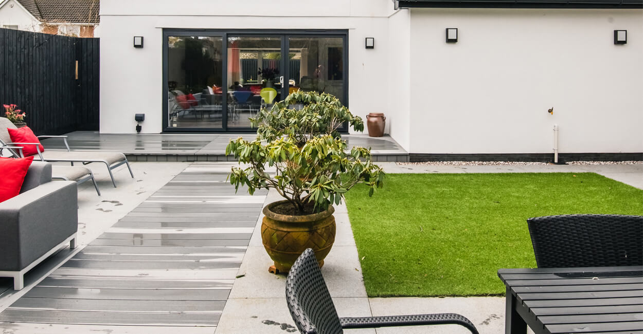 Low-maintenance garden featuring artificial grass and composite decking, creating a neat, chessboard-like layout.