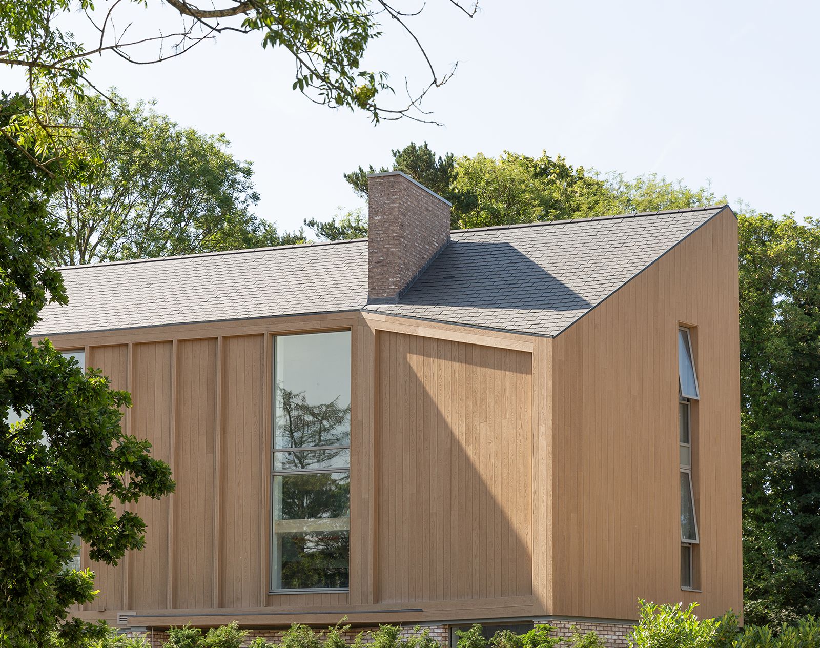 Contemporary house with vertical Millboard cladding in a natural wood finish, showcasing weather-resistant composite exterior panels.