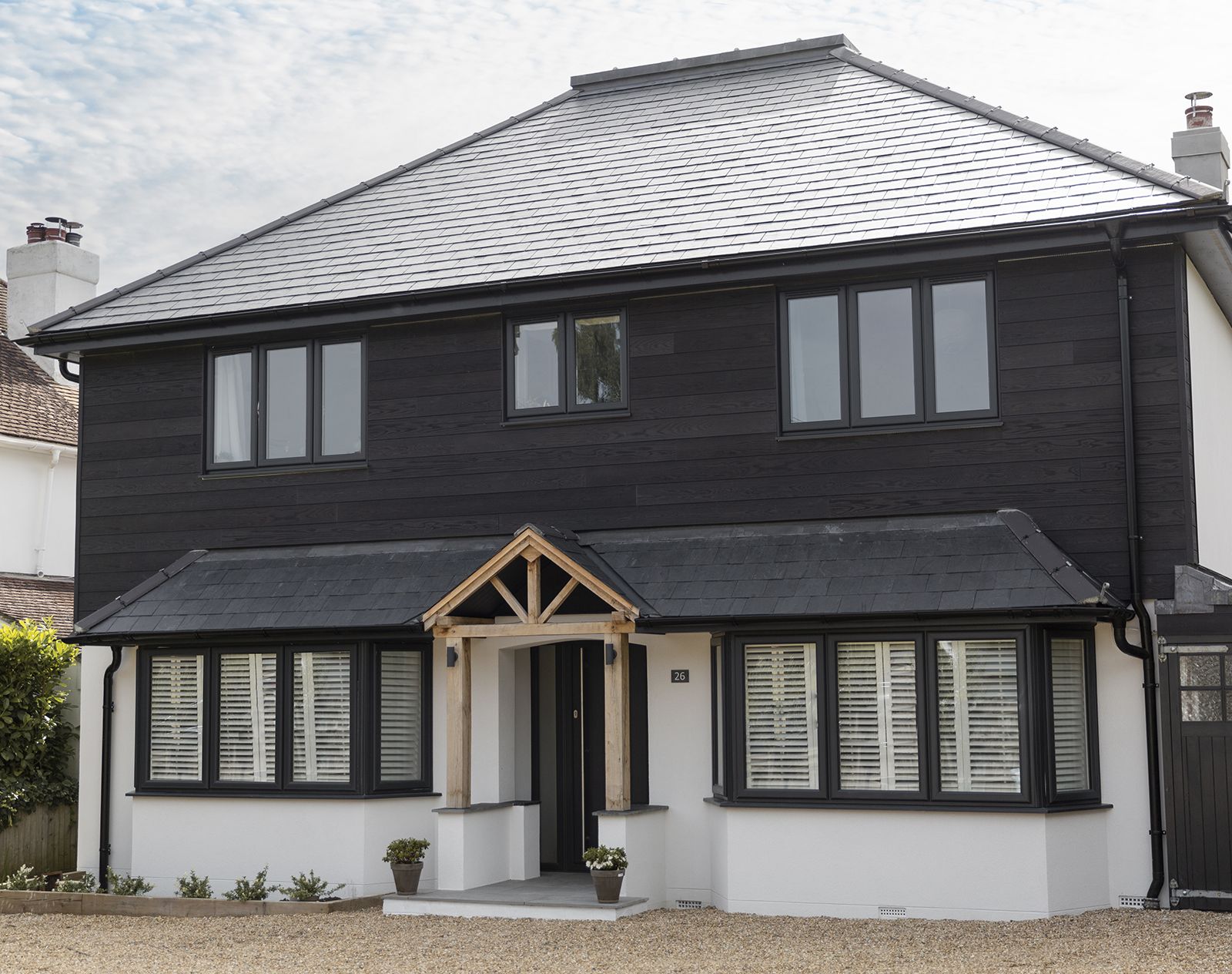 Modern two-storey home with charred-effect black Millboard cladding on the upper floor and white render below.