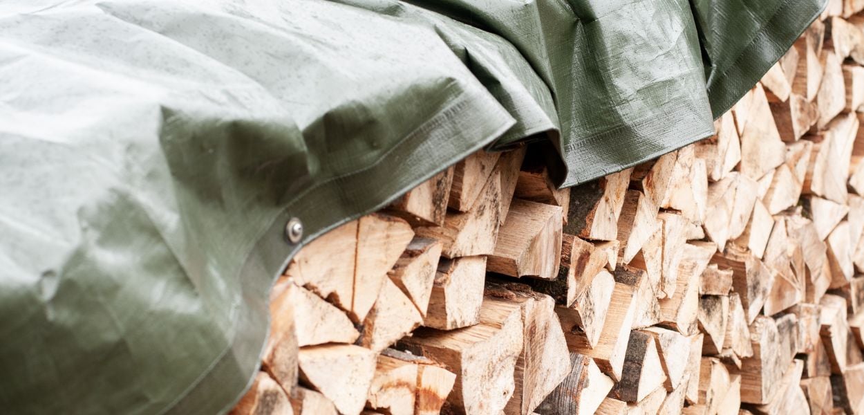 Green tarpaulin covering log stack