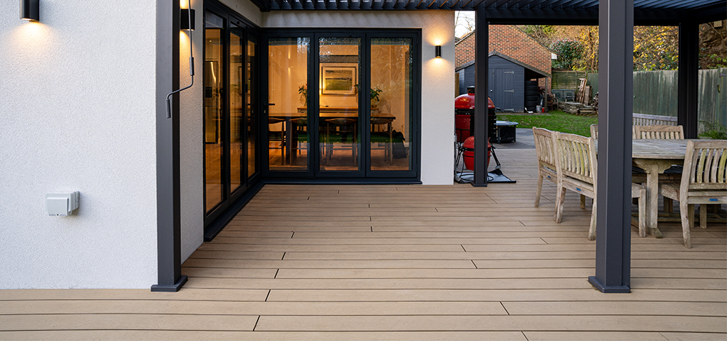 Outdoor eco friendly Composite Decking area beside glass sliding doors underneath a shelter.