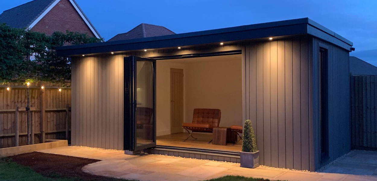 Contemporary garden room with Cladco Light Grey Composite Cladding, integrated spot lighting, and bi-fold doors, built by Wo-man Cave Ltd for a modern outdoor living space