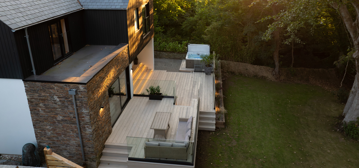 Side view of Millboard® Enhanced Grain limed oak decking with integrated hot tub in modern Cornish garden