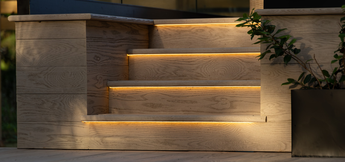 Detail of Millboard® Enhanced Grain limed oak decking steps with LED perimeter lighting for modern outdoor design