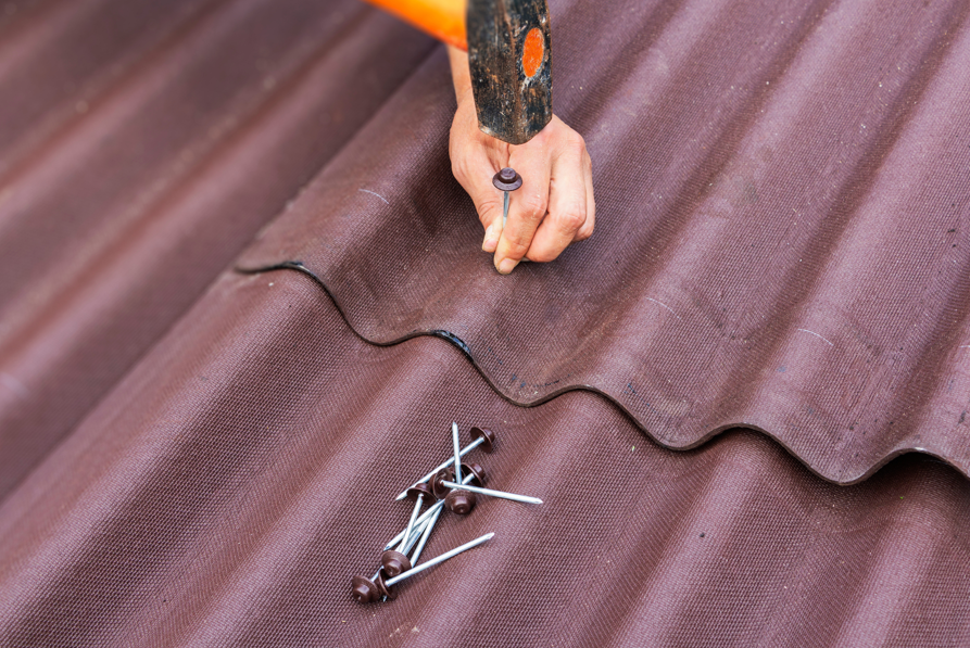 Corrugated onduline roofing panels being installed using nails