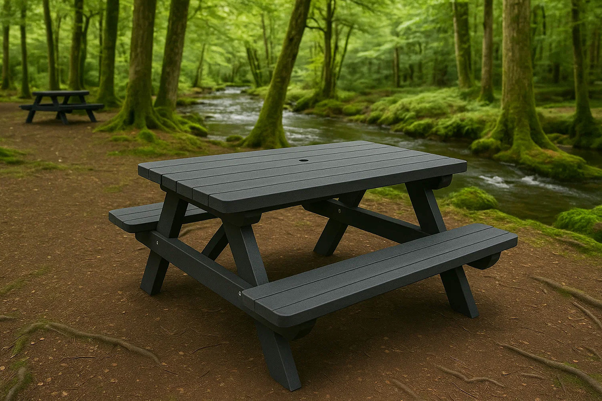 A-frame, recycled plastic picnic tables in a woodland picnic area next to a river.