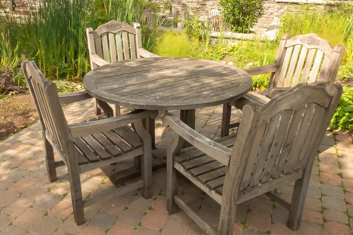 Wooden outdoor dining set on a stone tile patio.