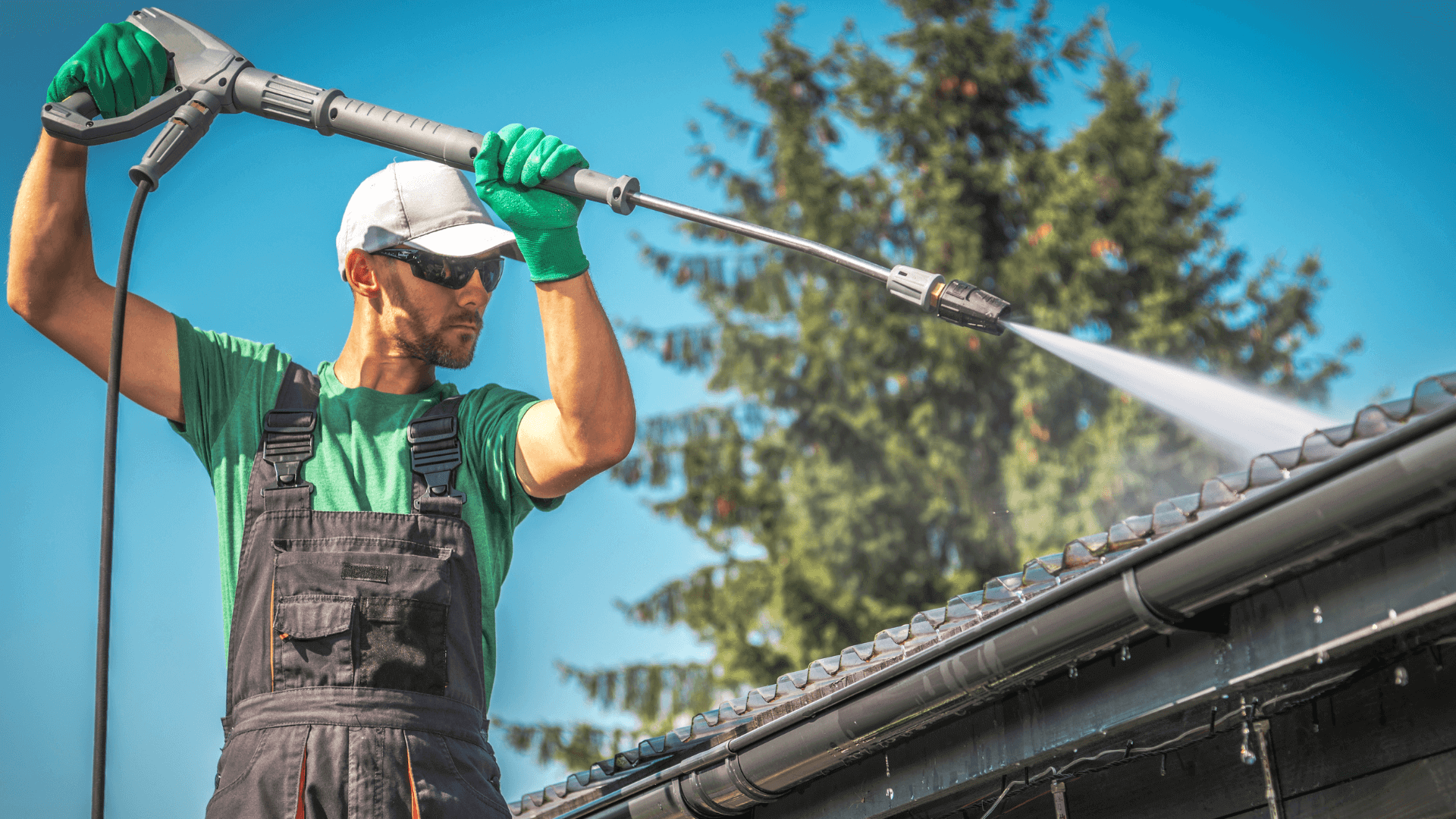 Man in overalls power washing some plastic roofing sheets