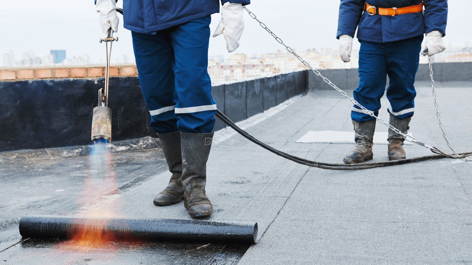 Two workmen using a blowtorch to install Bitumen roof sheets